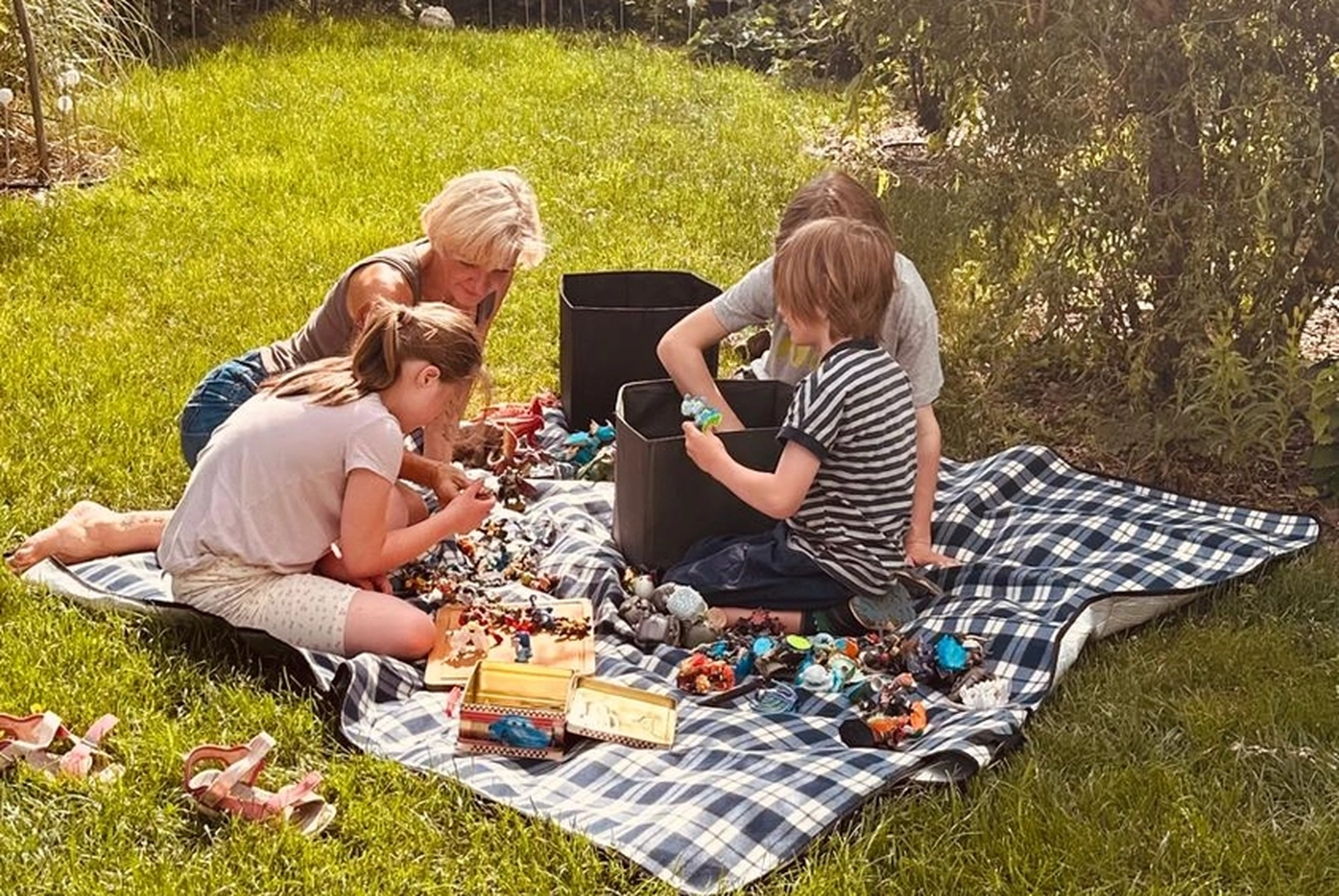 Allerbienen Celle - Betreuungsdienst - Eine Familie picknickt auf einer karierten Decke in einem Park.