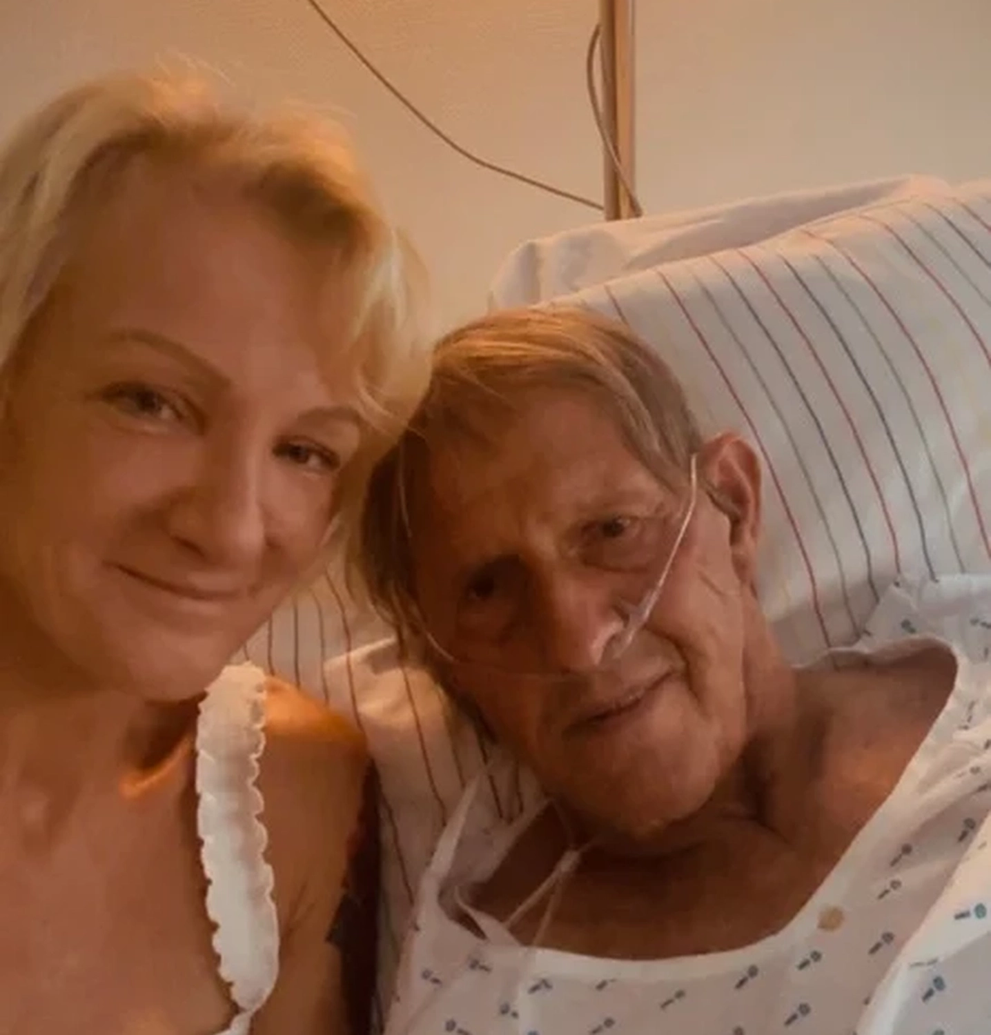 Allerbienen Celle - Betreuungsdienst - Eine blonde Frau lächelt freundlich neben einer älteren Person, die im Bett ruht.